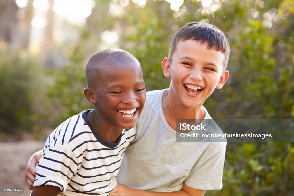 Portrait of two boys embracing and laughing hard outdoors Child Stock Photo