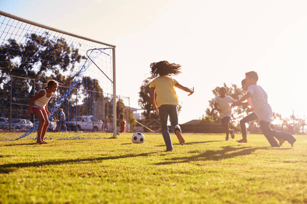 chica defensa de objetivo en el juego de fútbol con familiares y amigos - ball horizontal outdoors childhood fotografías e imágenes de stock