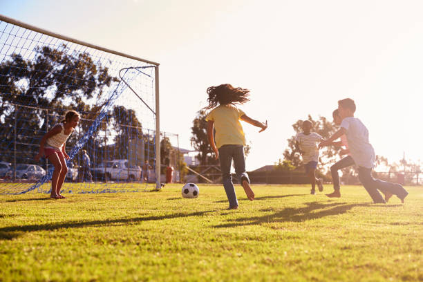 Girl defending goal at football game with family and friends Girl defending goal at football game with family and friends sports activity stock pictures, royalty-free photos & images