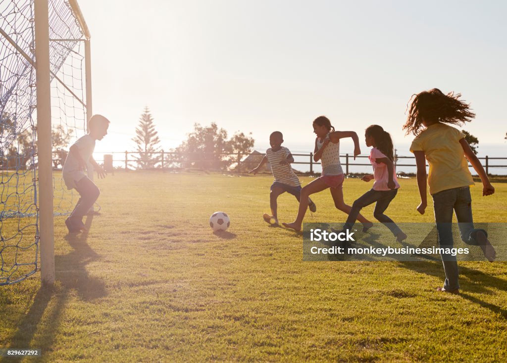 Kids playing football in a park, one in goal, side view Soccer Stock Photo