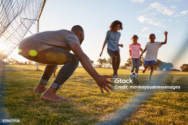 A Boy Kicks A Football During A Game With His Family Stock Photo - Download Image Now