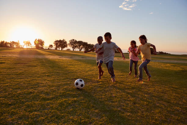 istock Four children chasing a ball during a game in a field 829630076