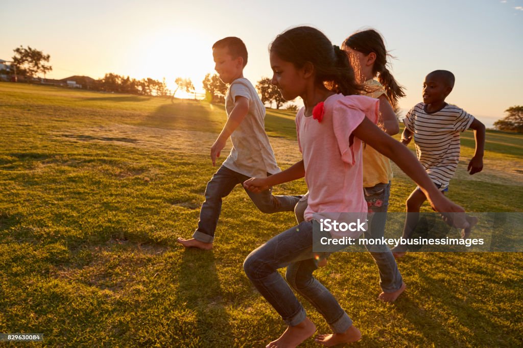 Cuatro niños corriendo descalzo en un parque - Foto de stock de Niño libre de derechos