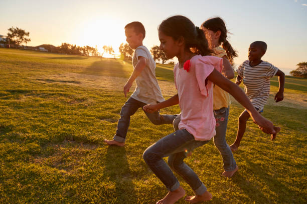 cuatro niños corriendo descalzo en un parque - sólo niñas fotografías e imágenes de stock