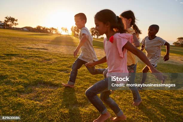 Cuatro Niños Corriendo Descalzo En Un Parque Foto de stock y más banco de imágenes de Niño - Niño, Correr, Bienestar