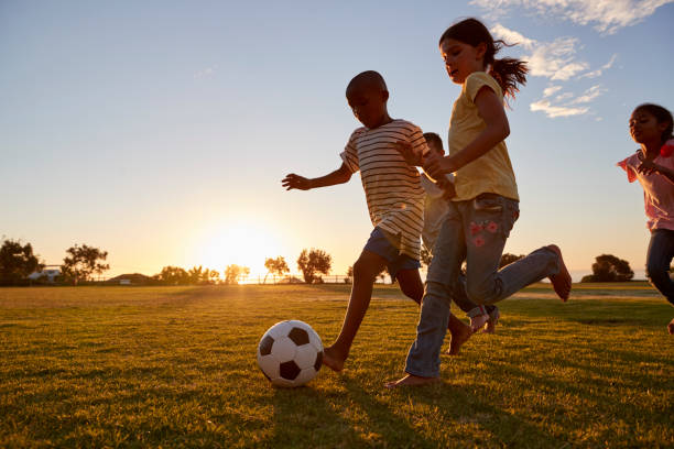 quatro crianças racing após uma bola de futebol que operam em condições de - child soccer sport playing - fotografias e filmes do acervo