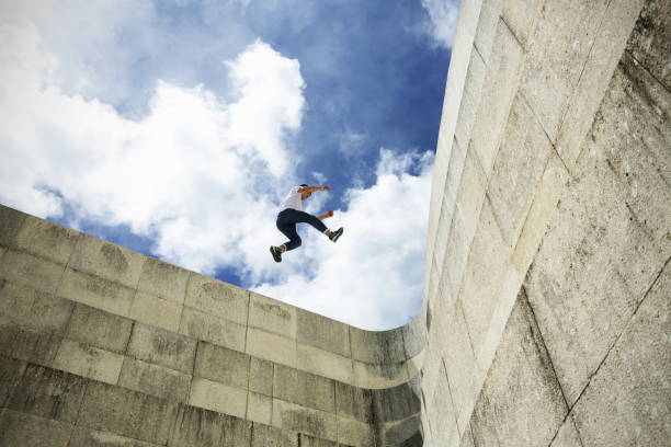 junger mann schritt springen auf betonwand - le parkour stock-fotos und bilder