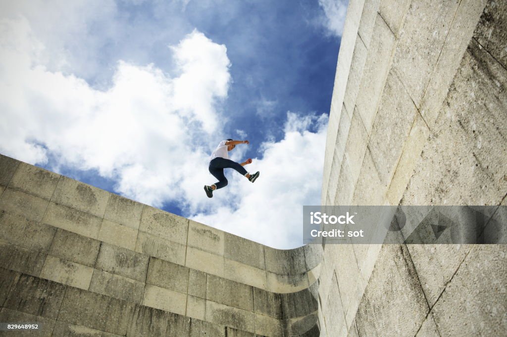 Young man stride jumping  on concrete wall Performer of the Parkour Free Running Stock Photo
