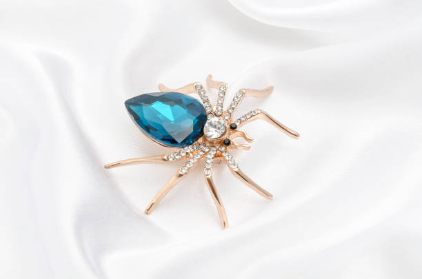istock Golden spider with a big blue stone on silk fabric 829655892