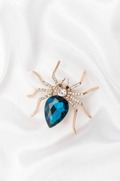 istock Golden spider with a big blue stone on silk fabric 829655930