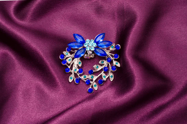 istock Silver flower brooch with blue diamonds on silk fabric 829656014
