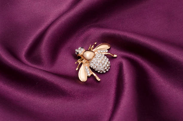 istock Golden brooch bee with diamonds on silk fabric 829656176