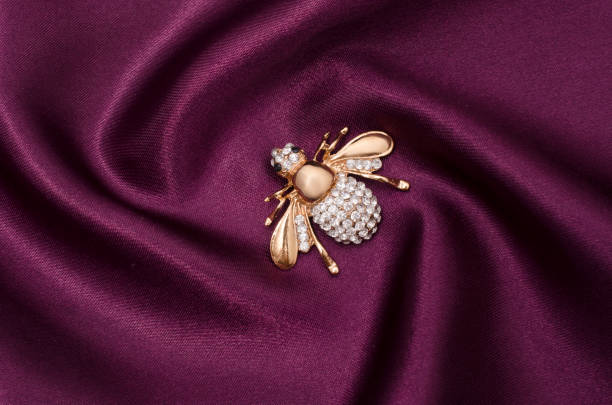 istock Golden brooch bee with diamonds on silk fabric 829656200