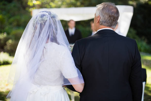 istock Bride standing with her father in park 829677988