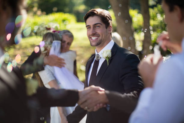 istock Groom shaking hand with guest in park 829682606