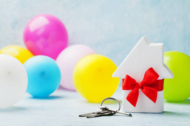 small white wooden house decorated red bow ribbon with bunch of keys and balloons. housewarming, gift, moving, real estate or buying a new home concept. - key real estate key ring house key imagens e fotografias de stock