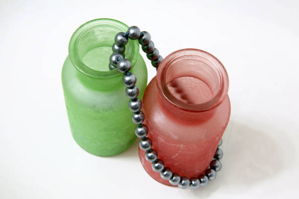 silver pearls flowing from green and pink frosted glass cosmetic containers