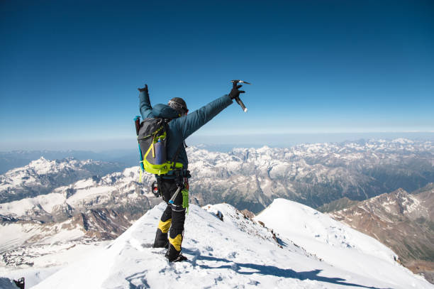 profesjonalny przewodnik hiker na szczycie skały z rękami do góry jest zadowolony z kolejnego zwycięstwa wznoszenia - on top of mountain peak success cold zdjęcia i obrazy z banku zdjęć