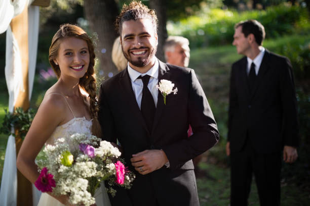istock Happy bride and groom standing in park 829720656