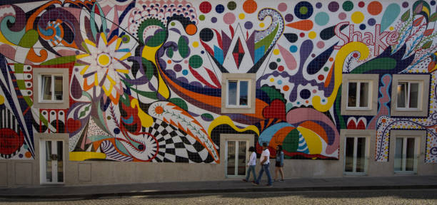 Setubal, Portugal - April 7, 2013: Graffiti on a wall. Street art is typical of this small streets of Portugal cities. Here painting on a wall of Alfama, Lisbon, with local people walking in the background.
