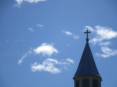church steeple in blue sky with clouds