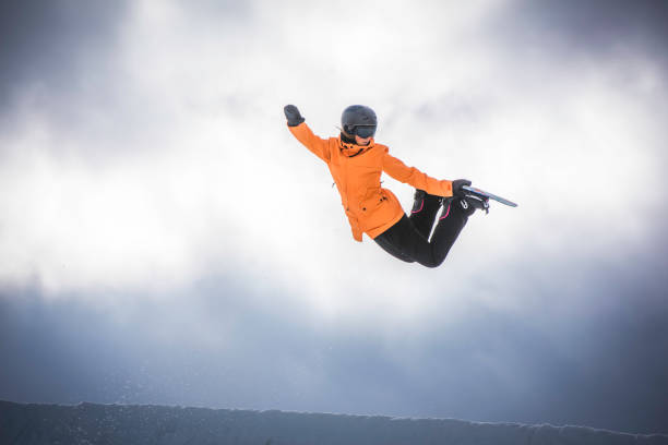 snowboarder donna a mezz'aria - skill side view jumping mid air foto e immagini stock
