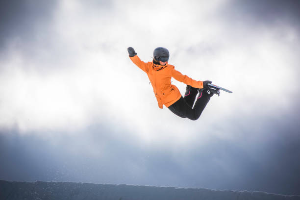 snowboarder feminino no ar - skill side view jumping mid air - fotografias e filmes do acervo