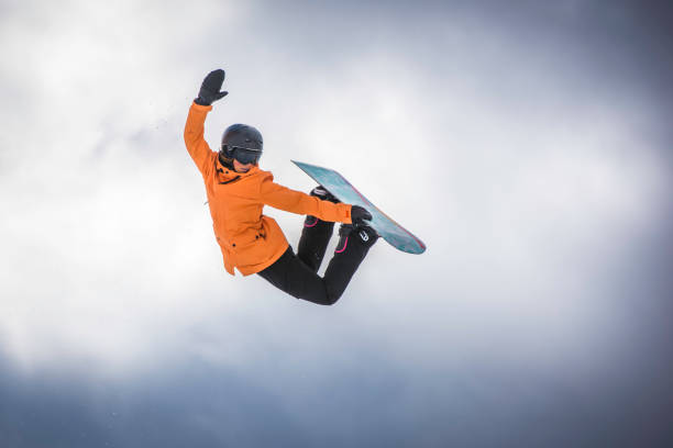 snowboarder donna a mezz'aria - skill side view jumping mid air foto e immagini stock