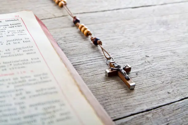 The book of Catholic Church liturgy and rosary beads on the wooden table