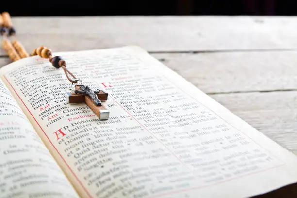 The book of Catholic Church liturgy and rosary beads on the wooden table