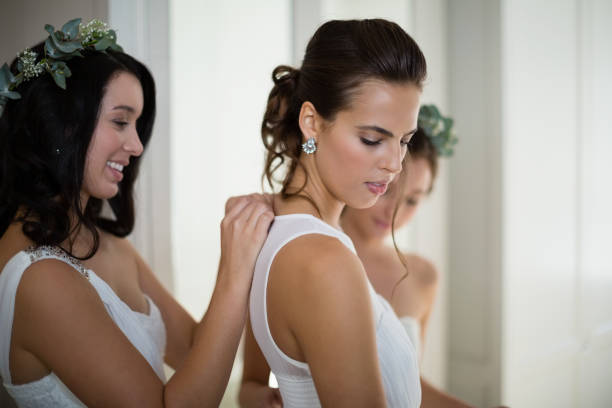 istock Bridesmaid assisting bride to dress 829775048