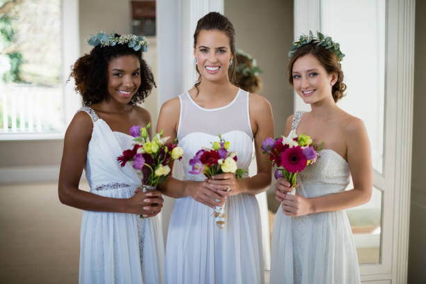 istock Bride and bridesmaids standing with bouquet at home 829775268