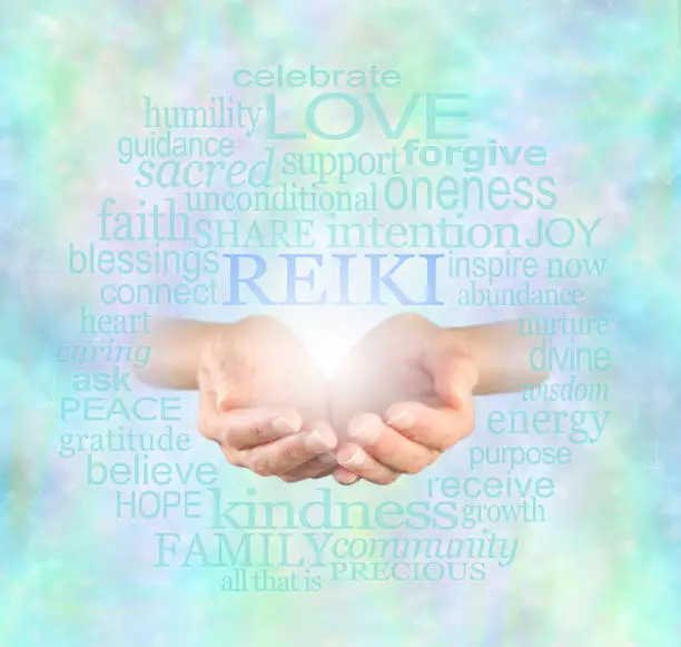Female hands cupped with the word 'Reiki' floating above, surrounded by a relevant healing word cloud on a misty sparkling ethereal blue energy background