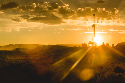 Dusk or Dawn image of a fracking drilling rig under a beautiful cloudscape and dreamy golden light