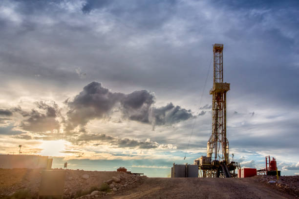 Fracking Drilling Rig at the Golden Hour Dusk or Dawn image of a fracking drilling rig under a beautiful cloudscape and dreamy golden light north dakota stock pictures, royalty-free photos & images