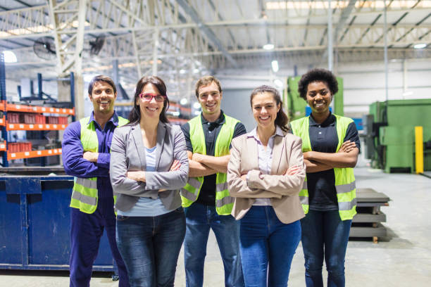 Portrait of staff at distribution warehouse Group portrait of staff at distribution warehouse. Warehouse team standing with arms crossed in factory. manufacturing occupation photos stock pictures, royalty-free photos & images