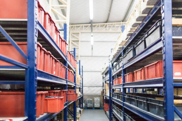 Long shelves factory warehouse with with boxes and containers. Interior of industrial warehouse.