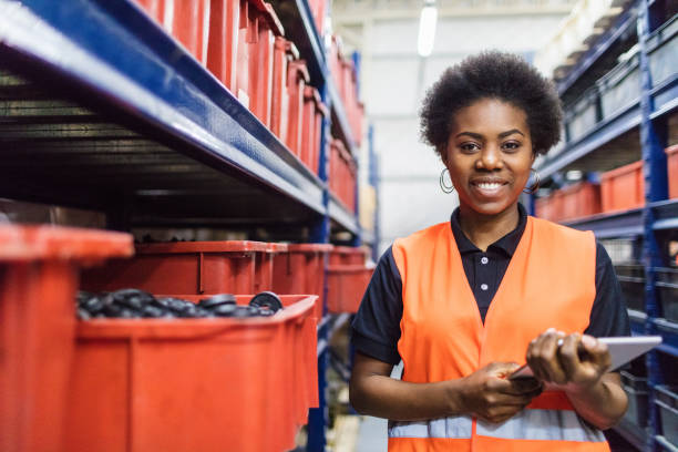 Supervisor stocktaking in company warehouse Portrait of african female foremen standing in warehouse aisle with digital tablet. Warehouse supervisor stocktaking in stock room. distribution warehouse photos stock pictures, royalty-free photos & images