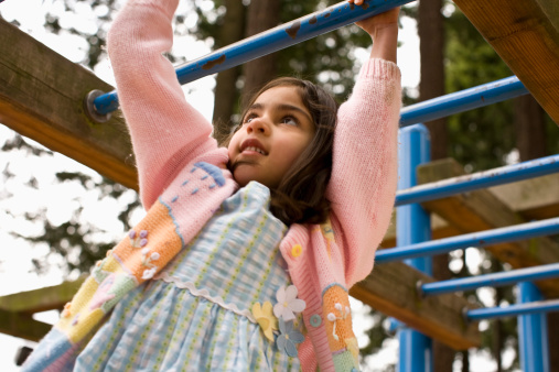 girl playing on monkey bars on jungle gym in playground
