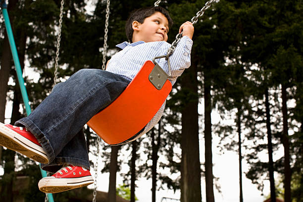 kids on swing en el parque - warnock fotografías e imágenes de stock