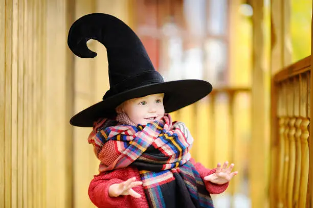 Toddler boy in pointed hat playing outdoors. Little wizard. Halloween concept