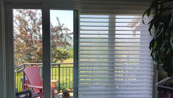 Bedroom deck with sheer horizontal blinds. One side up. One side down.