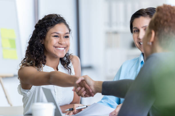 Office manager interviews potential new employee Confident young woman interviews for a position in an office. She is greeting the office manage. She is smiling confidently. job interview stock pictures, royalty-free photos & images
