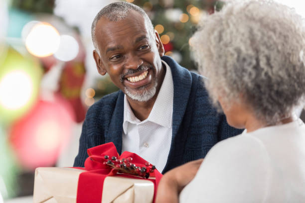 istock Senior man smiles while giving his wife a Christmas present 829917336