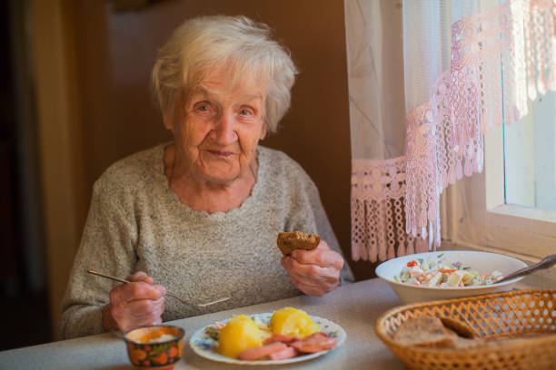 istock An elderly woman eats sitting at the table. 829938644