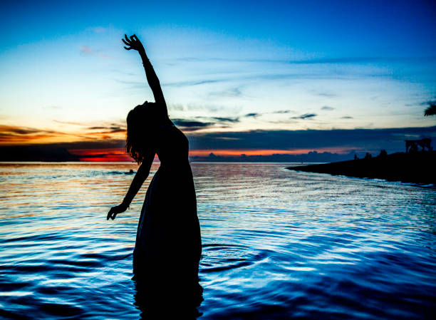 istock Woman Silhouette Dancing in Ocean Water 829972326