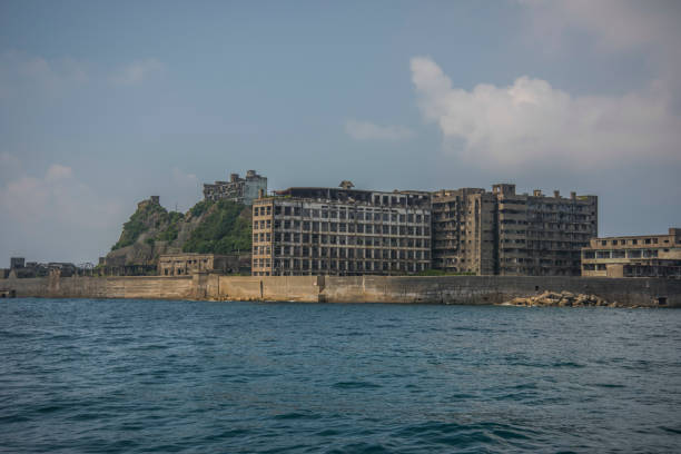 Battleship Island (Gunkanjima, Hashima, Gunkanjima, Gunkanjima, Gunkanjima) Hashima Island (端島 or simply Hashima — -shima is a Japanese suffix for island), commonly called Gunkanjima (軍艦島; meaning Battleship Island), is an abandoned island lying about 15 kilometers (9 miles) from the city of Nagasaki, in southern Japan. It is one of 505 uninhabited islands in Nagasaki Prefecture. The island's most notable features are its abandoned concrete buildings, undisturbed except by nature, and the surrounding sea wall. While the island is a symbol of the rapid industrialization of Japan, it is also a reminder of its dark history as a site of forced labor prior to and during the Second World War. hashima island photos stock pictures, royalty-free photos & images