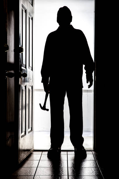 istock Intruder at door, in silhouette with hammer 830008020