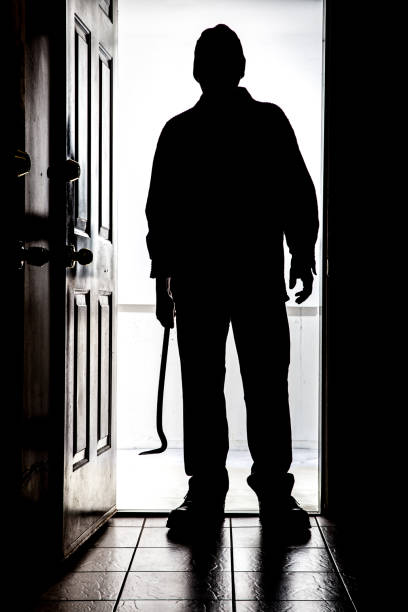 istock Intruder at door, in silhouette with crowbar 830008036