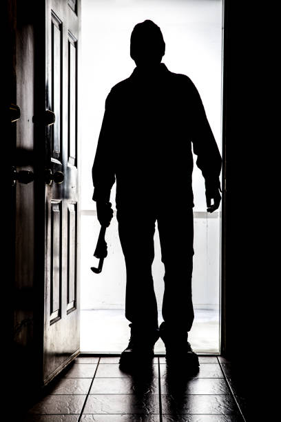 istock Intruder at door, in silhouette with pipe wrench 830008056